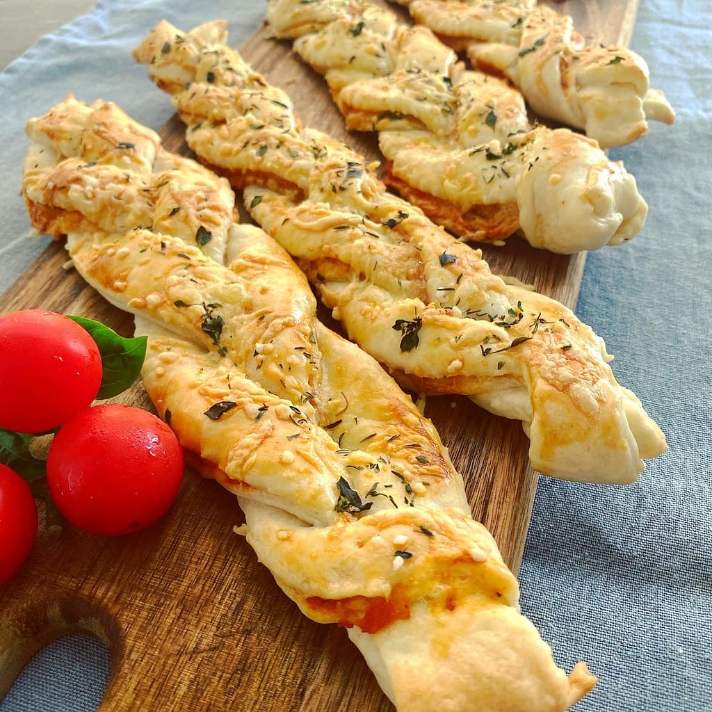 Bild zeigt gebackene Mürgteig Zöpfe gefüllt mit Tomaten und Schinken